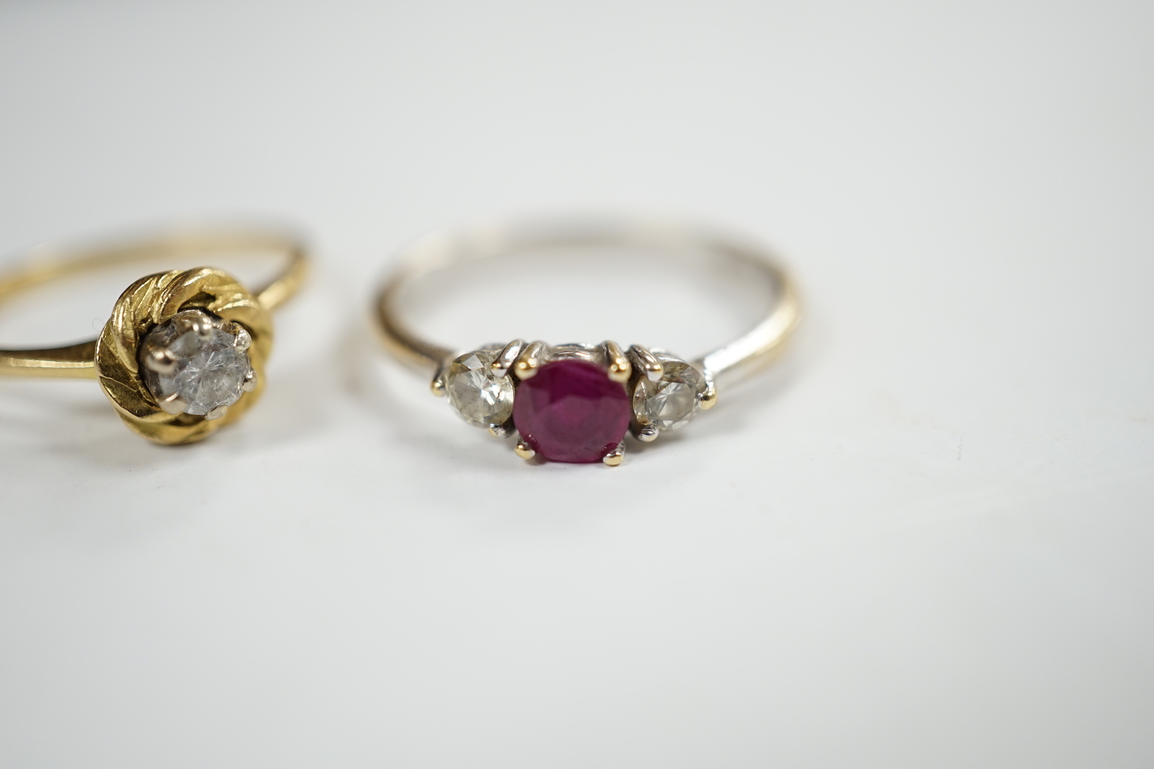 A modern 18ct white gold, ruby and diamond set three stone ring, size N/O and a 1970's 18ct gold and solitaire diamond set ring, size L, gross weight 5.3 grams.